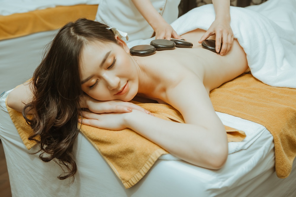 Massage Đá Nóng Tại Vinpearl Khách hàng thư giãn khi massage đá nóng với đá basalt đặt trên lưng Massage đá nóng